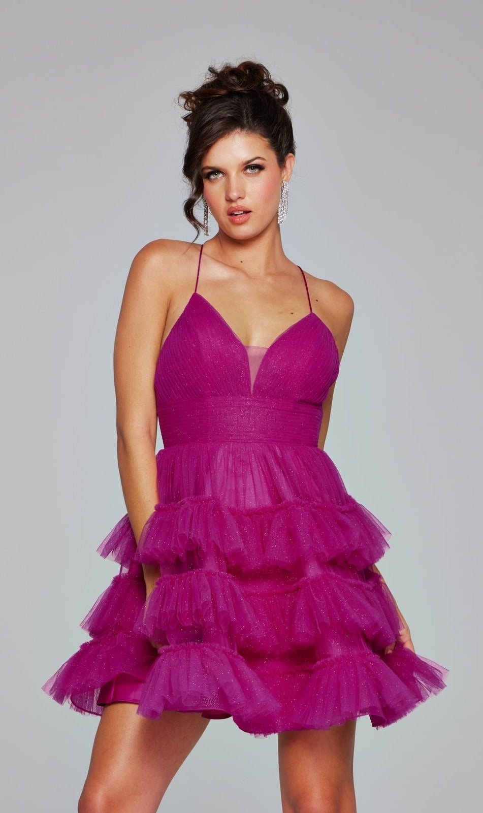 Woman wearing the Short Ruffled A-Line Hoco Dress: Jovani 39655, a sleeveless deep pink designer dress with spaghetti straps and tiered tulle, standing against a plain light gray background.